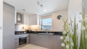 Una cocina moderna con armarios grises, encimera negra, horno integrado y ventana con vistas.
