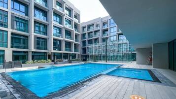 A modern building with a swimming pool and a wooden deck.