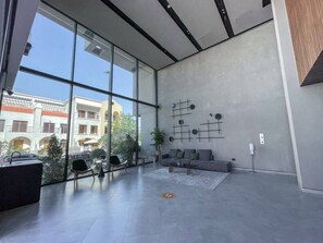 A modern lobby with large windows, a seating area with sofas, and a minimalist decor.
