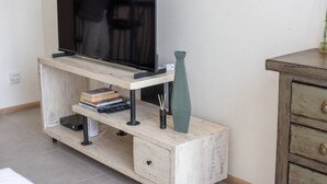 A wooden TV stand with a flat-screen TV, a vase, and books.