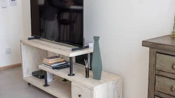 A wooden TV stand with a flat-screen TV, a vase, and books.
