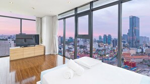 Una habitación de hotel moderna con una cama grande, televisión y vistas a la ciudad.