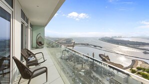 Ein Balkon mit Glasgeländern, mit Blick auf einen Fluss und eine Baustelle.