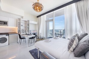 A modern hotel room with a large bed, a desk, and a view of the city.