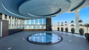 A modern indoor pool area with a circular design, large windows, and potted plants. - Danube Miraclz 2903 · Breathtaking view compact & modern spacious studio (Arjan)
