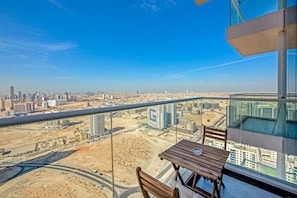 A high-rise balcony with a clear view of a cityscape, including a highway and multiple buildings.