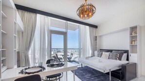 A modern bedroom with a large bed, a dining table, and a view of the city. - Danube Miraclz 2903 · Breathtaking view compact & modern spacious studio (Arjan)