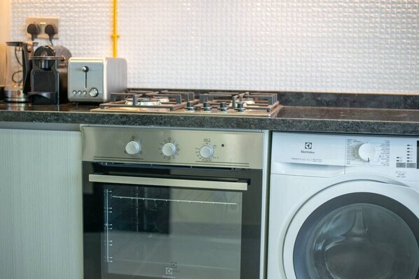 A kitchen with a stove, oven, and washing machine.
