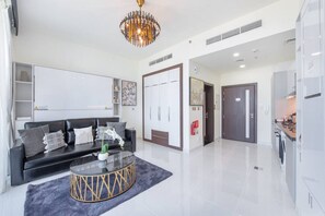 A modern living room with a black sofa, a glass coffee table, and a chandelier. - Danube Miraclz 2903 · Breathtaking view compact & modern spacious studio (Arjan)