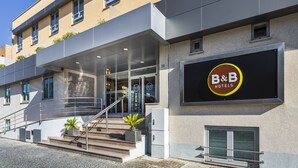 Un hotel tipo B&B con una fachada moderna, una escalera que lleva a la entrada y un cielo despejado.