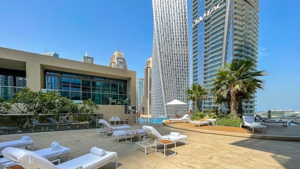 Eine Dachterrasse mit Liegestühlen und Pool, umgeben von Hochhäusern.