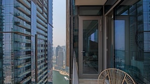 Ein Hochhaus mit einem Balkon, ausgestattet mit einem Korbstuhl und einer Glastür zu einem Innenraum.