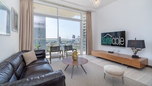 Un salon moderne avec un canapé en cuir, une table basse ronde et un téléviseur posé sur une console en bois.