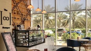 Un café moderne avec un plafond en bois, de grandes fenêtres et des chaises bleues.