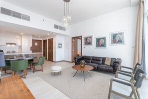 Un salon moderne avec un canapé, des fauteuils, une table basse et des œuvres d’art accrochées aux murs.