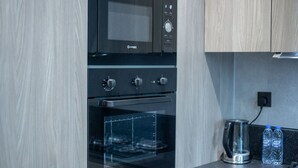 A modern kitchen with a built-in microwave, oven, and glass-fronted oven. - JVC-Signature Livings 103 N · Modern flat with KING SIZE bed and HIGH SPEED Wifi (Dubai)