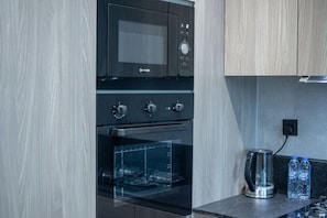 Una cocina moderna con microondas integrado, horno y horno con puerta de vidrio.