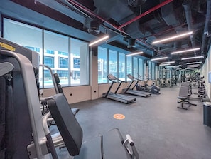 Un gimnasio con cintas de correr, máquinas de pesas y un amplio ventanal.