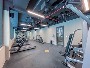 Un gimnasio con cintas de correr, máquinas de pesas y equipo de ejercicio.
