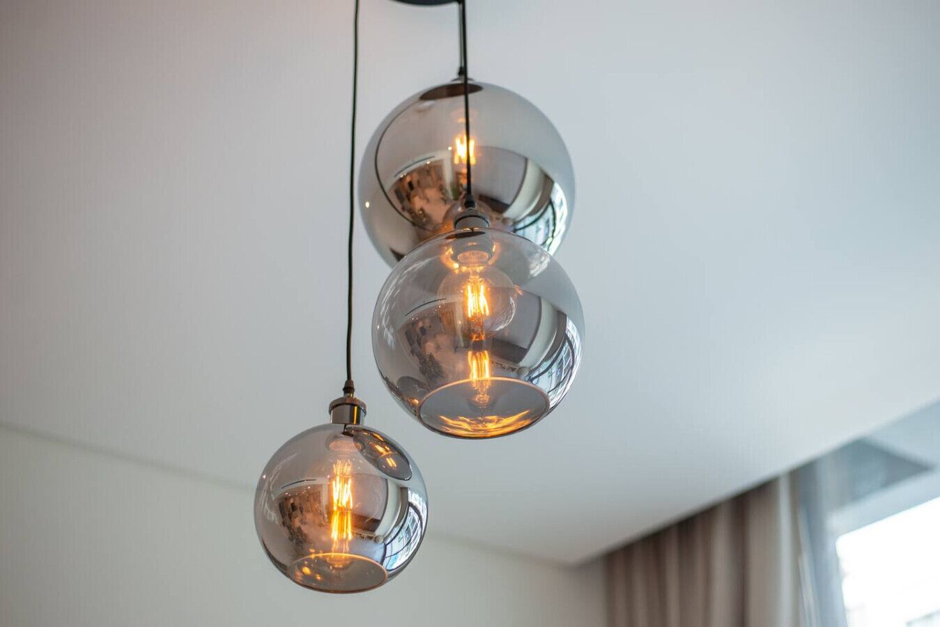 Three spherical pendant lights with exposed bulbs hanging from a ceiling.