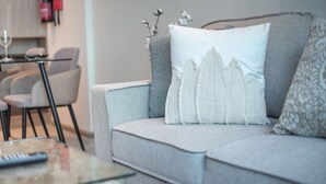 A modern living room with a grey sofa, a glass coffee table, and a remote control. - JVC-Signature Livings 103 N · Modern flat with KING SIZE bed and HIGH SPEED Wifi (Dubai)