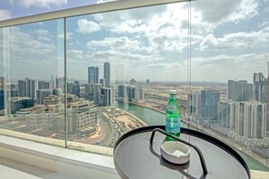 Une chambre située dans un immeuble de grande hauteur, avec vue sur la ville, une bouteille d’eau et un petit cendrier.
