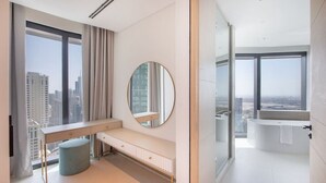 Ein modernes Badezimmer mit einer großen Badewanne, einem runden Spiegel und einem Waschtisch mit Sitzbank.