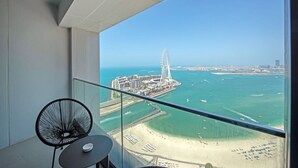 Ein Balkon mit freiem Blick auf eine Küstenstadtlandschaft, darunter ein großes Riesenrad und ein Strand.
