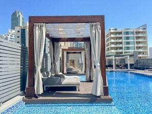 Un espace piscine sur le toit, doté d’un auvent, d’un lit et offrant une vue sur le paysage urbain.