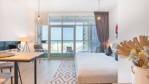 A hotel room with a bed, a desk, a chair, a lamp, and a view of the beach. - Studio One 913 Dubai Marina · Funky STUDIO Dubai Marina outstanding facilities (Dubai Marina)