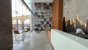 A modern reception area with a glass counter, seating area, and a colorful geometric wall design. - Studio One 913 Dubai Marina · Funky STUDIO Dubai Marina outstanding facilities (Dubai Marina)