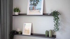Two shelves with framed pictures, a potted plant, and a cactus.