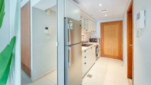A narrow kitchen with a refrigerator, microwave, and cabinets.