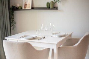 A dining table set with plates, glasses, and cutlery, with chairs around it.