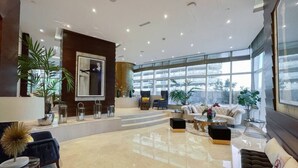 Un vestíbulo amplio con techo alto, ventanas grandes y mobiliario moderno.