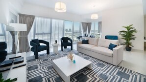 Una sala de estar moderna con un sofá, dos sillones, una mesa de centro y un ventanal con vistas a la ciudad.