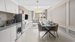 Una cocina moderna con lavadora, un comedor con mesa y sillas, y un amplio ventanal.