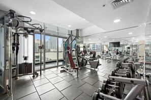 Une salle de sport moderne dotĂ©e de divers Ă©quipements dâentraĂźnement, de grandes fenĂȘtres et offrant une vue sur la ville.