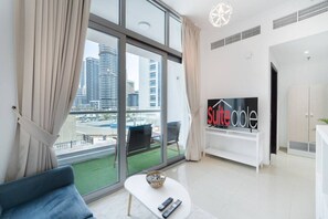 A modern living room with a large window, a sofa, a small table with a bowl, and a TV displaying 'suiteable' on the wall.