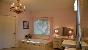 A bathroom with a bathtub, a sink, a vanity with a mirror, and a chandelier. - Large home, perfect for family reunions (Ingram)