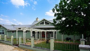 A green house with a covered porch and a fenced yard. - Large home, perfect for family reunions (Ingram)