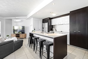 Enjoy a spacious kitchen with a sink, ample counter space, and a comfortable seating area with a sofa and flat-screen TV.