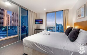 Enjoy a city view from the balcony, featuring a large bed and flat-screen TV.