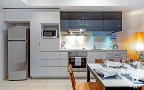 Enjoy cooking in this well-lit kitchen with a microwave, stainless steel refrigerator, and small oven.