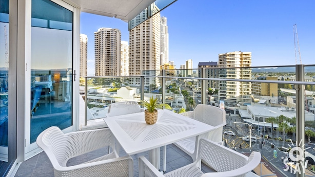 A balcony with white wicker furniture, a small table, and a potted plant. - H'Residences – Cozy 2 Bed Hinterland View — Q Stay (Surfers Paradise)