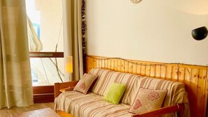 Ein gemütliches Zimmer mit einer Holzsofa, einem Holztisch und einem Fenster mit Vorhängen.