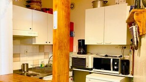 Eine kleine Küche mit weißen Schränken, einer Holzarbeitsplatte, einer Kaffeemaschine, einer Mikrowelle und einem Geschirrspüler.