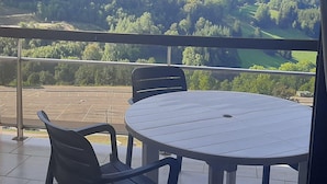 Ein Balkon mit Tisch und Stühlen mit Blick auf eine gebirgige Landschaft.