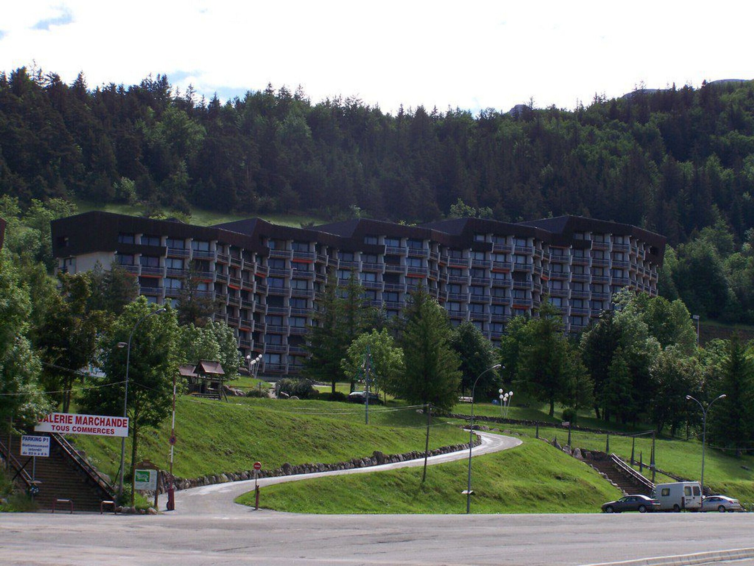 Ein mehrstöckiges Hotel mit modernem Design, gelegen in einer grünen, hügeligen Landschaft.