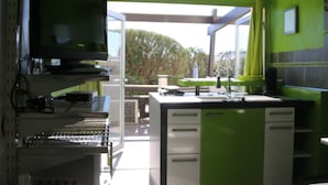 A modern kitchen with a large island, a flat-screen TV, and a view of the outdoors. - Cozy Air-Conditioned Studio for 2 with Terrace & Parking in Agde (Cap d'Agde naturisme)